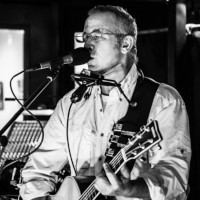 Steve Robert playing guitar and singing